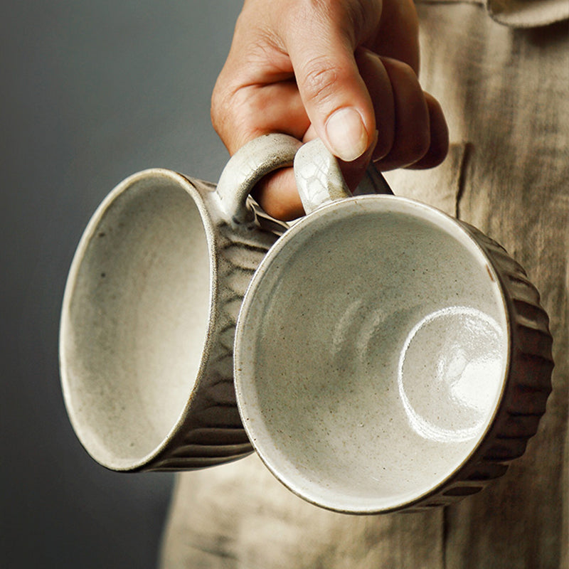 person holding 2 rough vintage ceramic mugs