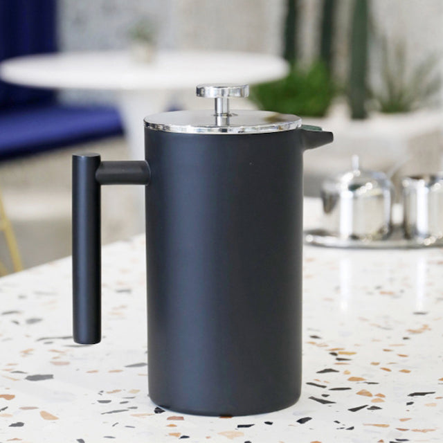Black stainless steel french press with filter on counter